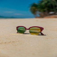 Des lunettes de soleil avec une monture rouge sur le sable