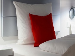 Deux oreillers blancs et un coussin rouge posés sur un mobilier