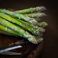 Des asperges étalées sur une surface en bois