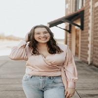 Une femme ronde à la mode avec une blouse légèrement décolletée et une paire de jeans