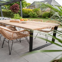 Sur une terrasse, des fauteuils en rotin et une table en bois sur laquelle un bol de fruits et une plante sont posés.