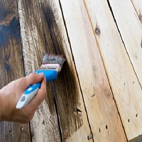 Une personne qui passe du vernis sur du bois