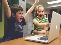Deux enfants qui jouent sur un laptop de la marque Apple