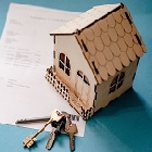 Une petite maison en maquette et une clé sur un papier