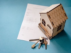 Une petite maison en maquette et une clé sur un papier
