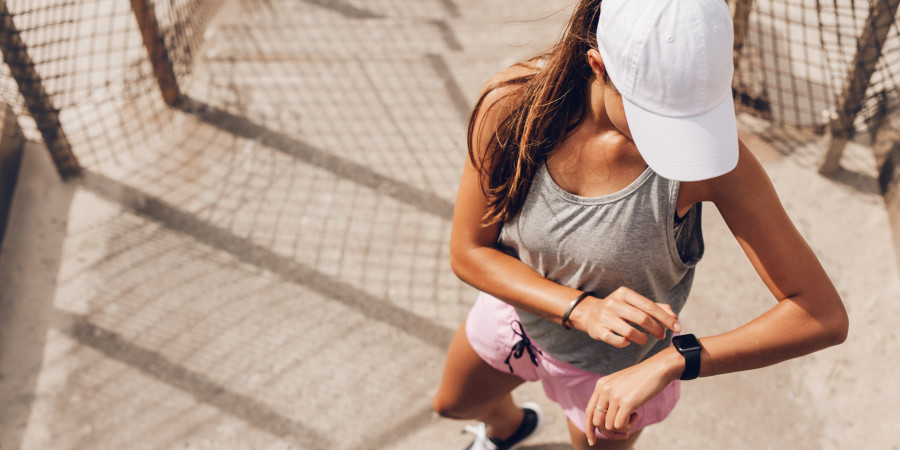 Femme joggeuse en tenue de sport qui regarde sa montre connectée