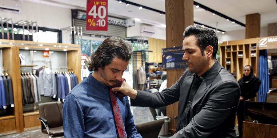Un jeune iranien qui essaie une cravate dans un magasin de mode 
