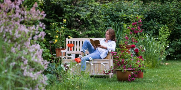 Une femme qui lit un livre dans son jardin