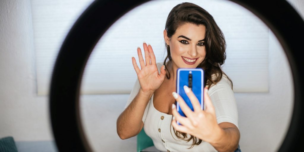 Une jeune femme qui se prend en selfie avec son smartphone en utilisant des filtres de beauté
