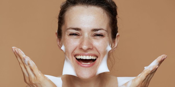 Une femme qui se nettoie le visage avec de la mousse pour enlever l’acné