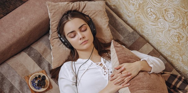 Une jeune femme qui écoute un podcast pour mieux dormir