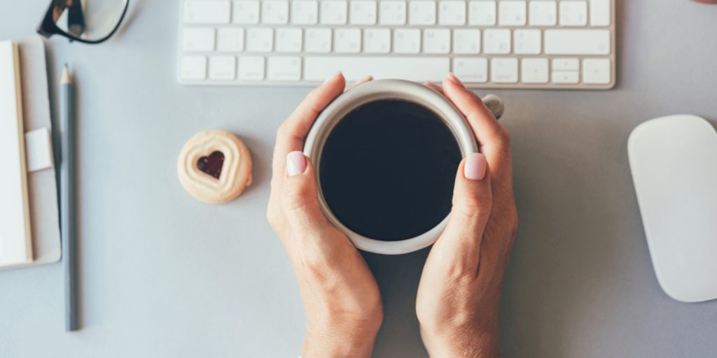 Des mains posées sur une tasse de café