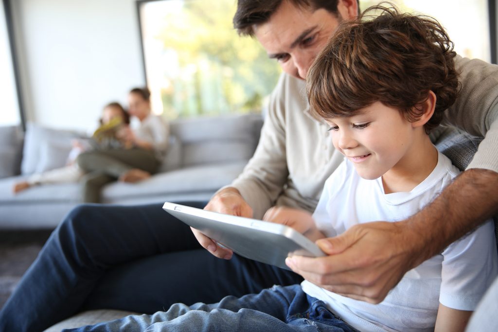Un parent qui regarde une tablette avec son enfant 