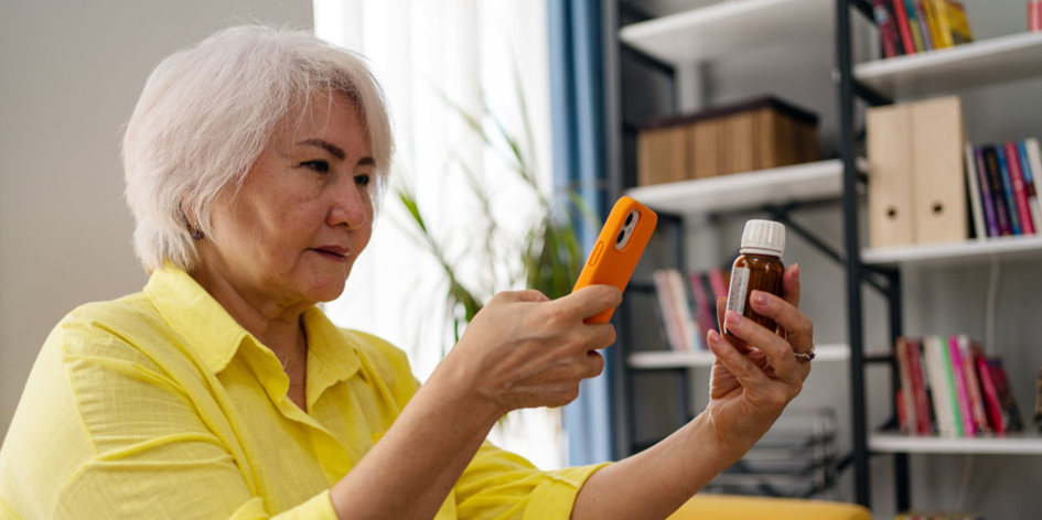 Femme agee utilisant un iphone pour photographier un flacon de medicament 