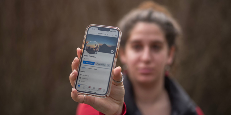 Femme tenant un smartphone avec un profil Facebook sur l’ecran 