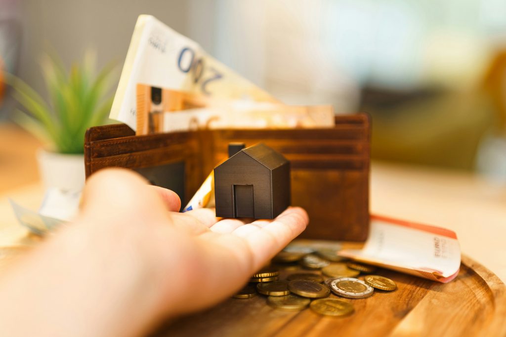 Miniature de maison et billets illustrant l’approche foncière de HERELES en financement alternatif